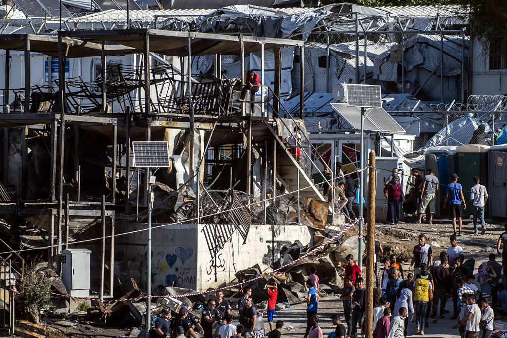 Migranten vor zerstörten Containern im Migrantenlager von Moria auf der griechischen Insel Lesbos (Bild: Angelos Tzortzinis/AFP)