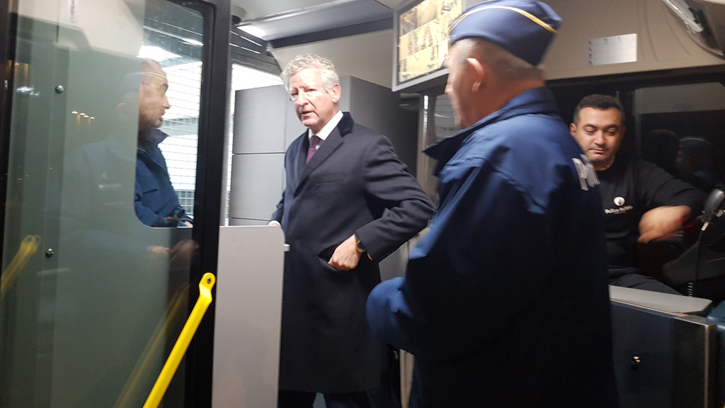 Minister De Crem mit zwei Polizisten im Bus