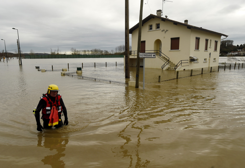 Feuerwehrmann watet durch überschwemmte Straße