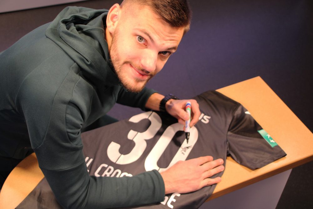 Torhüter Hendrik Van Crombrugge signiert sein Trikot vom Spiel zwischen der AS Eupen und Anderlecht (Bild: Katrin Margraff/BRF)