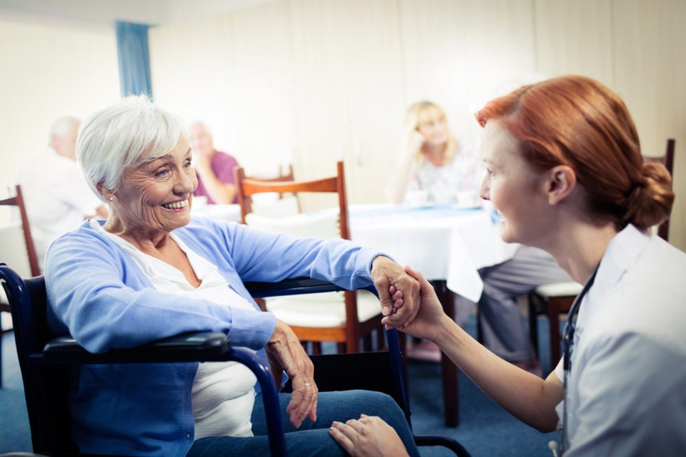 Pflegerin mit Seniorin im Rollstuhl