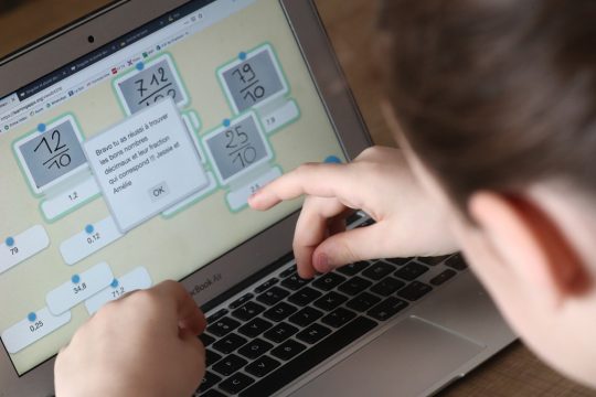 Kind löst Rechenaufgaben am Laptop