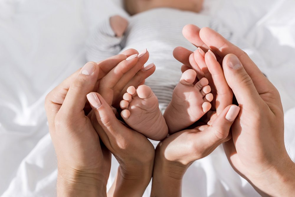 Eltern halten die Füße ihres Neugeborenen