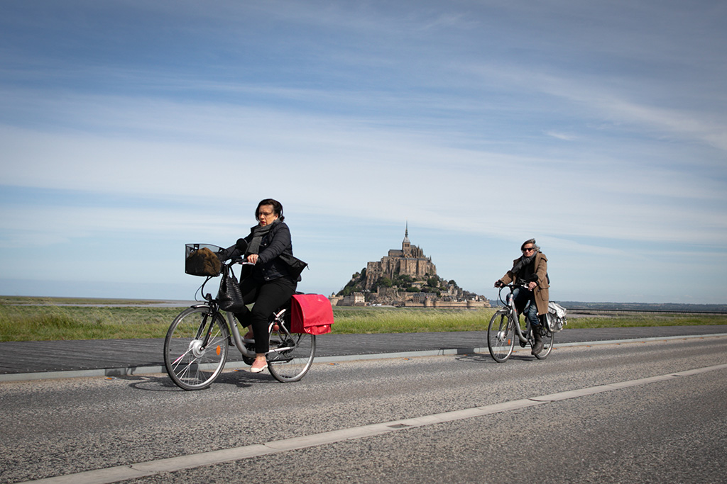 Fahrradfahrerinnen vor dem Mont-Saint-Michel (Bild: Lou Benoist/AFP)
