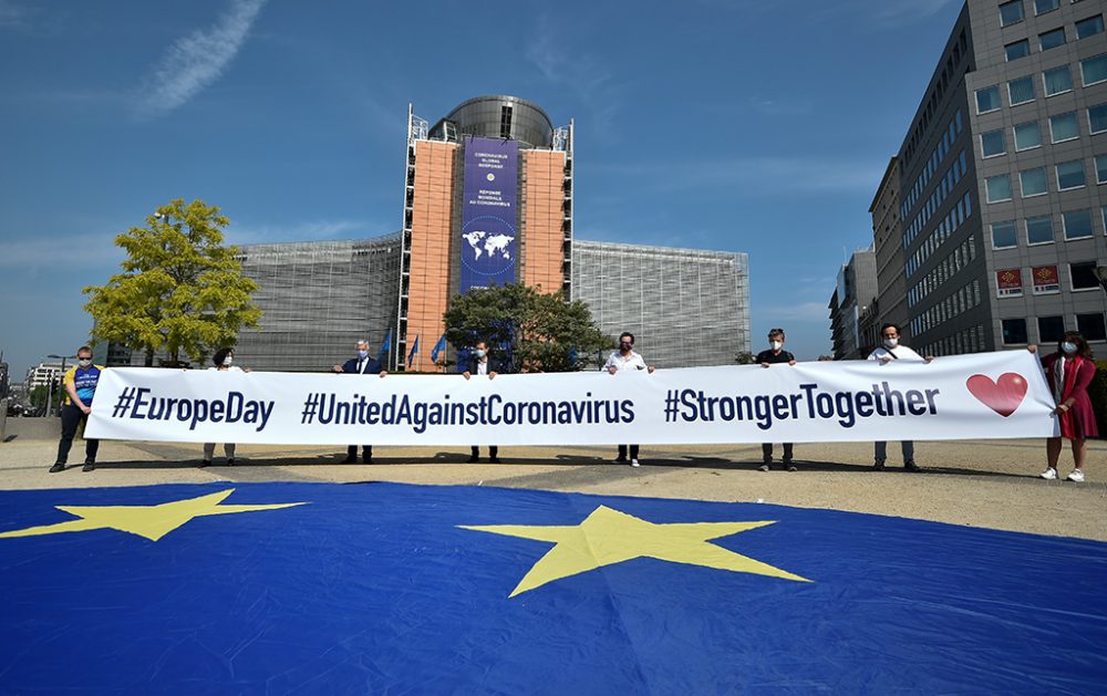 dier Reynders (3v.l.) und Mitarbeiter der EU-Kommission - alle mit Masken - halten ein Spruchband am Schuman-Kreisverkehr in Brüssel fest (Bild: John Thys/AFP)