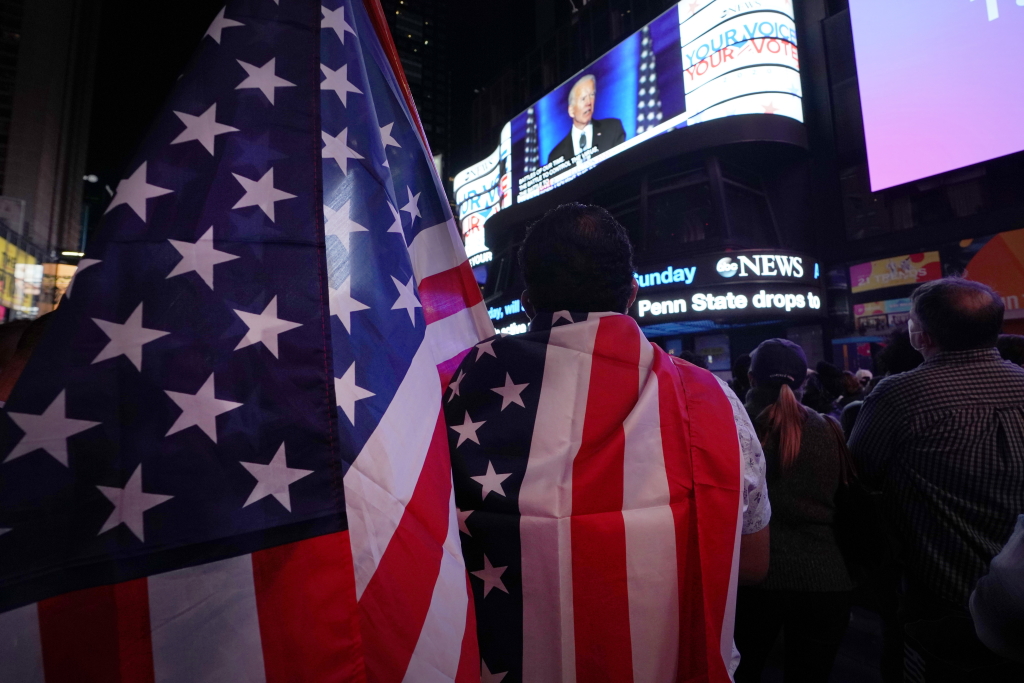 Times Square in New York: Menschen sehen die Siegesrede von Biden (Bild: Timothy A. Clary/AFP)