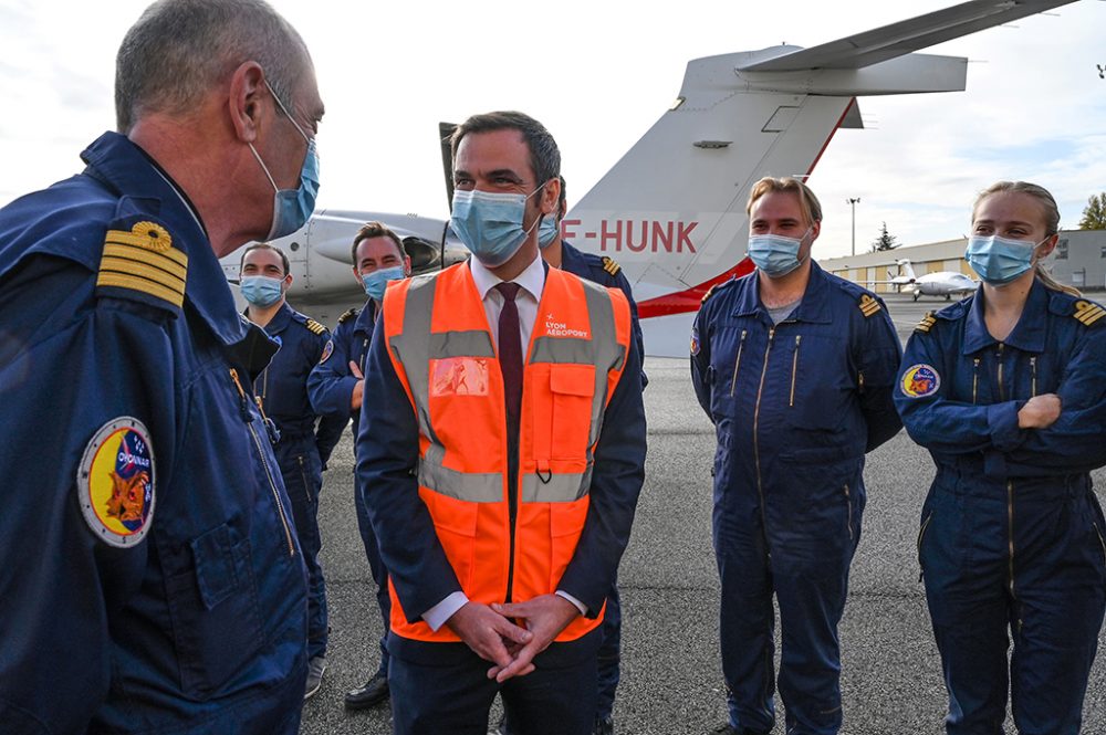 Frankreichs Gesundheitsminister Olivier Véran spricht mit Piloten von medizinischen Flugzeugen in der Nähe von Lyon (Bild: Philippe Desmazes/POOL/AFP)