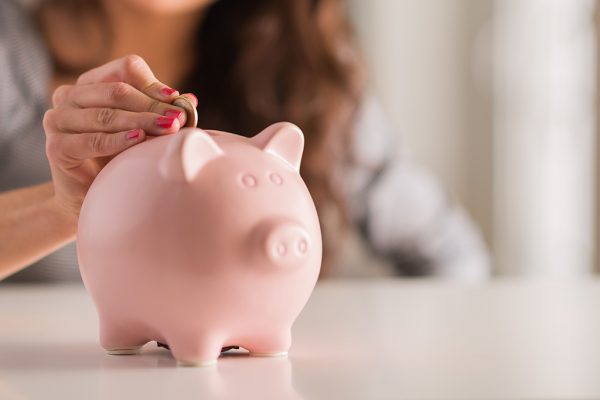 Frau steckt Münze in Sparschwein (© Bildagentur PantherMedia / Krakenimages)