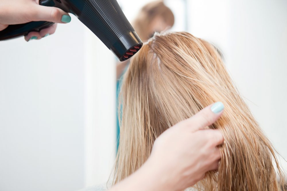 Friseurin fönt Haare einer Kundin