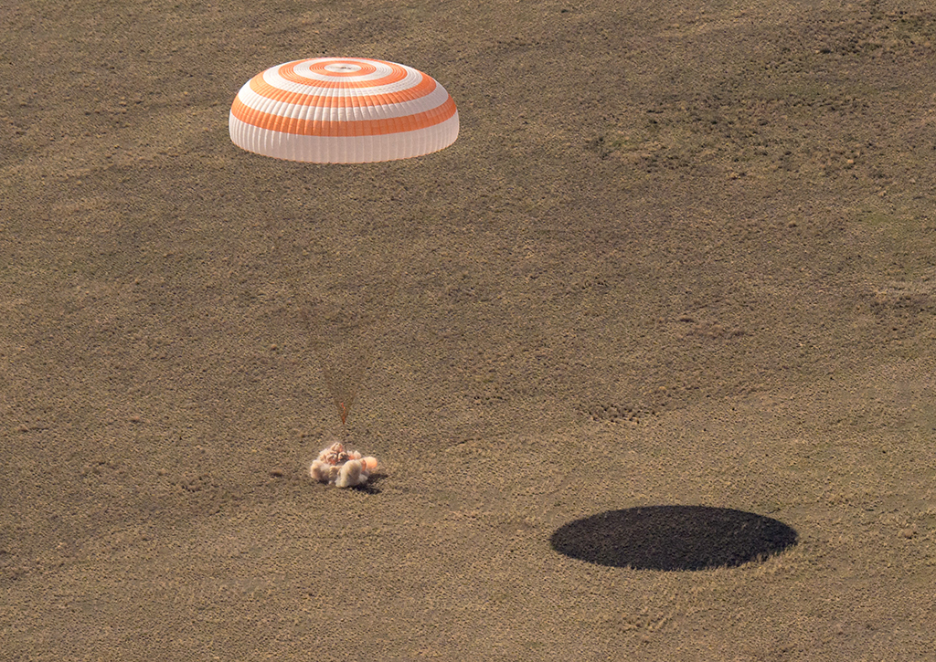 Die Kapsel mit den drei Raumfahrern schwebt kurz vor der Landung an einem riesigen Fallschirm (Bild: Nasa/AFP)