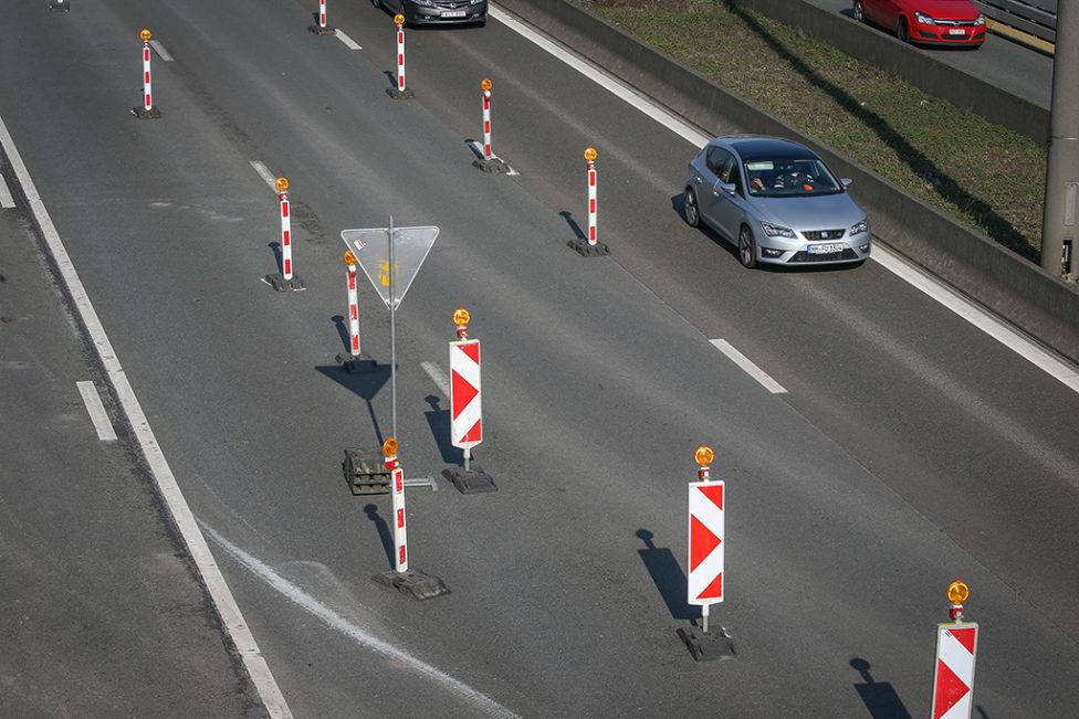 Auto fährt auf der linken Spur der Autobahn, auf der rechten Fahrbahnseite stehen Absperrbaken