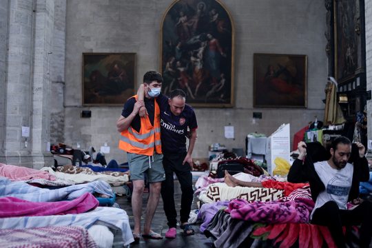 Ein ehrenamtlicher Helfer kümmert sich um einen der Hungerstreikenden in der Kirche Saint-Jean-Baptiste-au-Beguinage in Brüssel (Bild: Kenzo Tribouillard/AFP)
