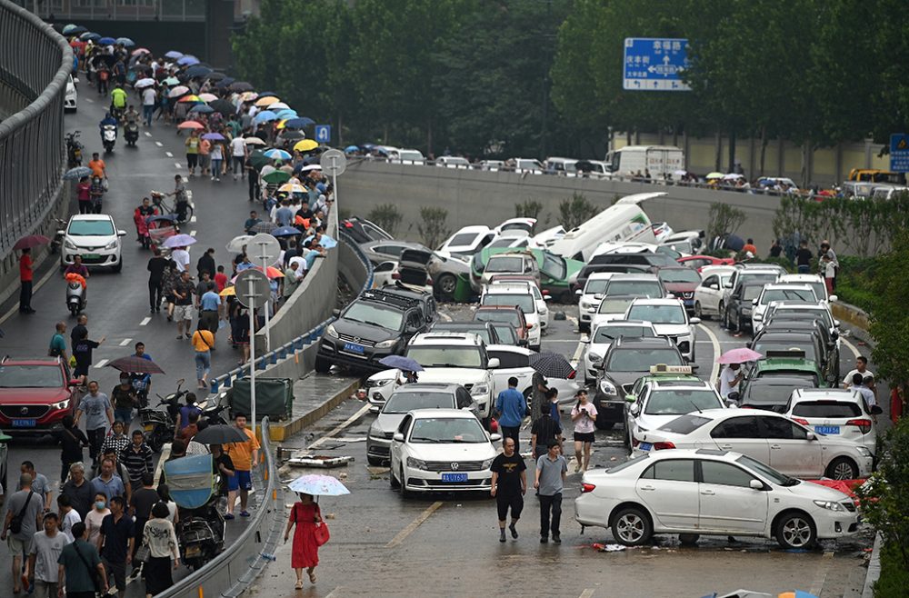 Schwere Überschwemmungen in Zentralchina: Leute schauen aufeinander gestapelte Fahrzeuge in Zhengzhou an (Bild: Noel Celis/AFP