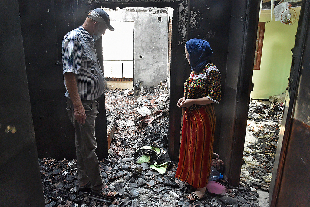 Algerier nahe Ait Daoud begutachten die Schäden, die das Feuer in ihrem Wohnhaus angerichtet hat (Bild: Ryan Kramdi/AFP)