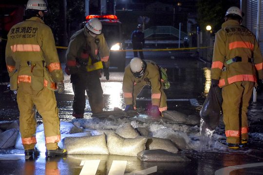 Feuerwehrmänner versuchen, eine geplatzte Wasserleitung nach dem Beben in Tokio (Bild: STR/Jiji Press/AFP)