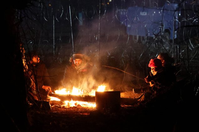 Migranten wärmen sich an der polnisch-belarussischen Grenze an einem Feuer (Bild: Maxim Guchek/Belta/AFP)