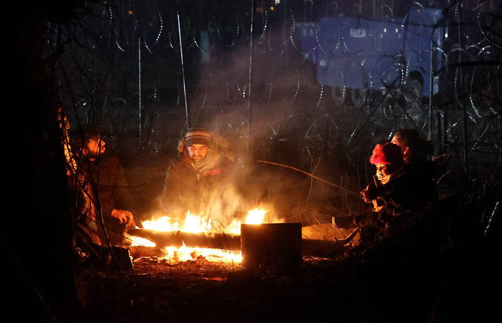 Migranten wärmen sich an der polnisch-belarussischen Grenze an einem Feuer (Bild: Maxim Guchek/Belta/AFP)