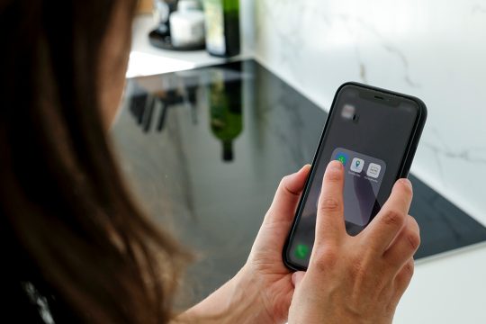 Frau mit Handy in der Küche