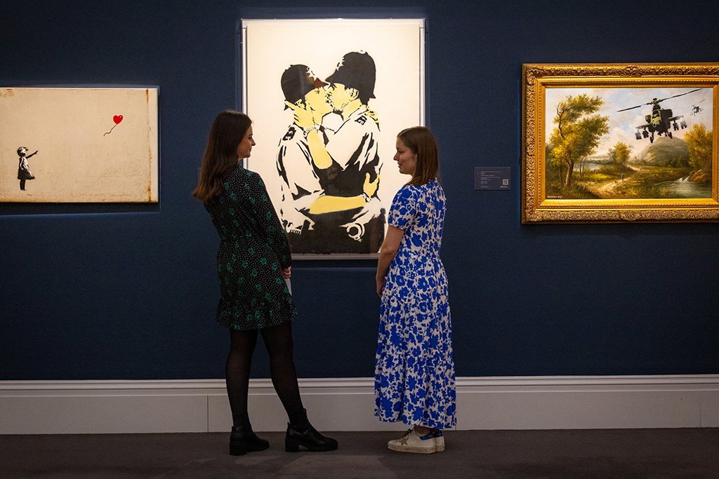 Das Gemälde "Kissing Coppers" von Banksy wird im Auktionshaus Sotheby's versteigert (Bild: Tolga Akmen/AFP)