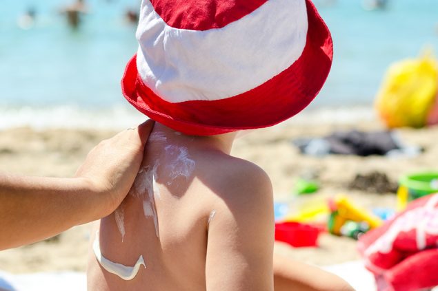 Junge lässt Sonnencreme auftragen