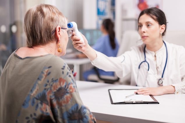 Ärztin und Patientin mit Infrarot-Thermometer