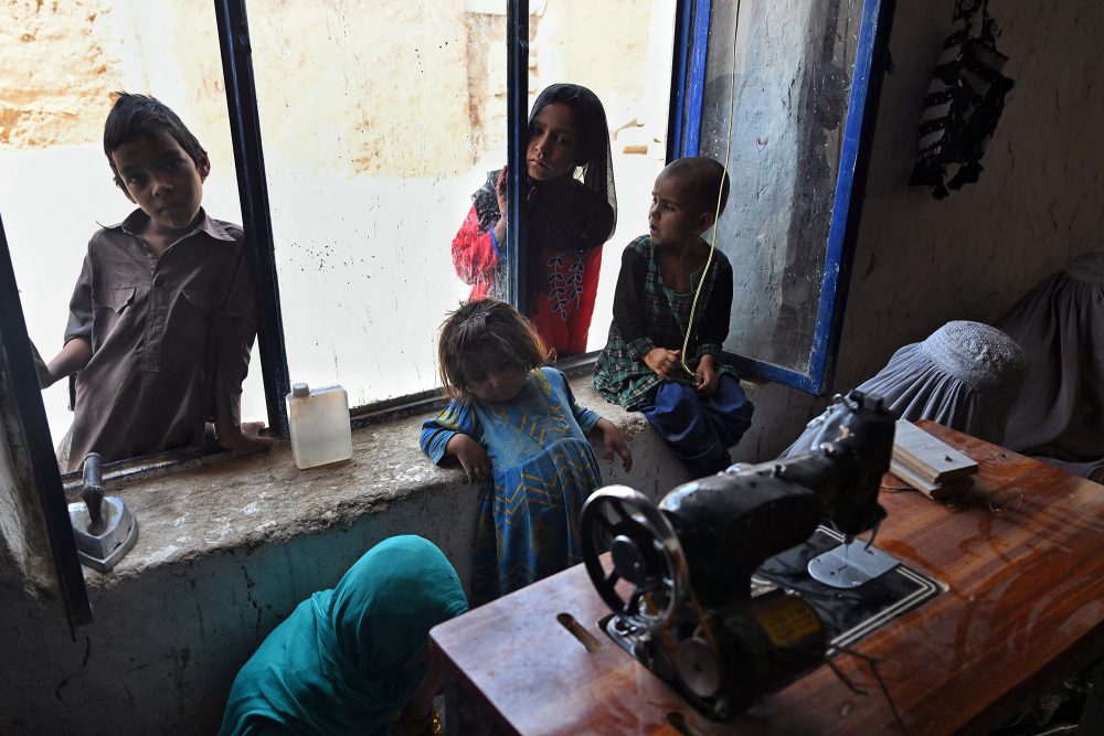 Kinder sehen Frauen beim Nähen zu, Kandahar, 30. Juli (Bild: Lillian Suwanrumpha/AFP)