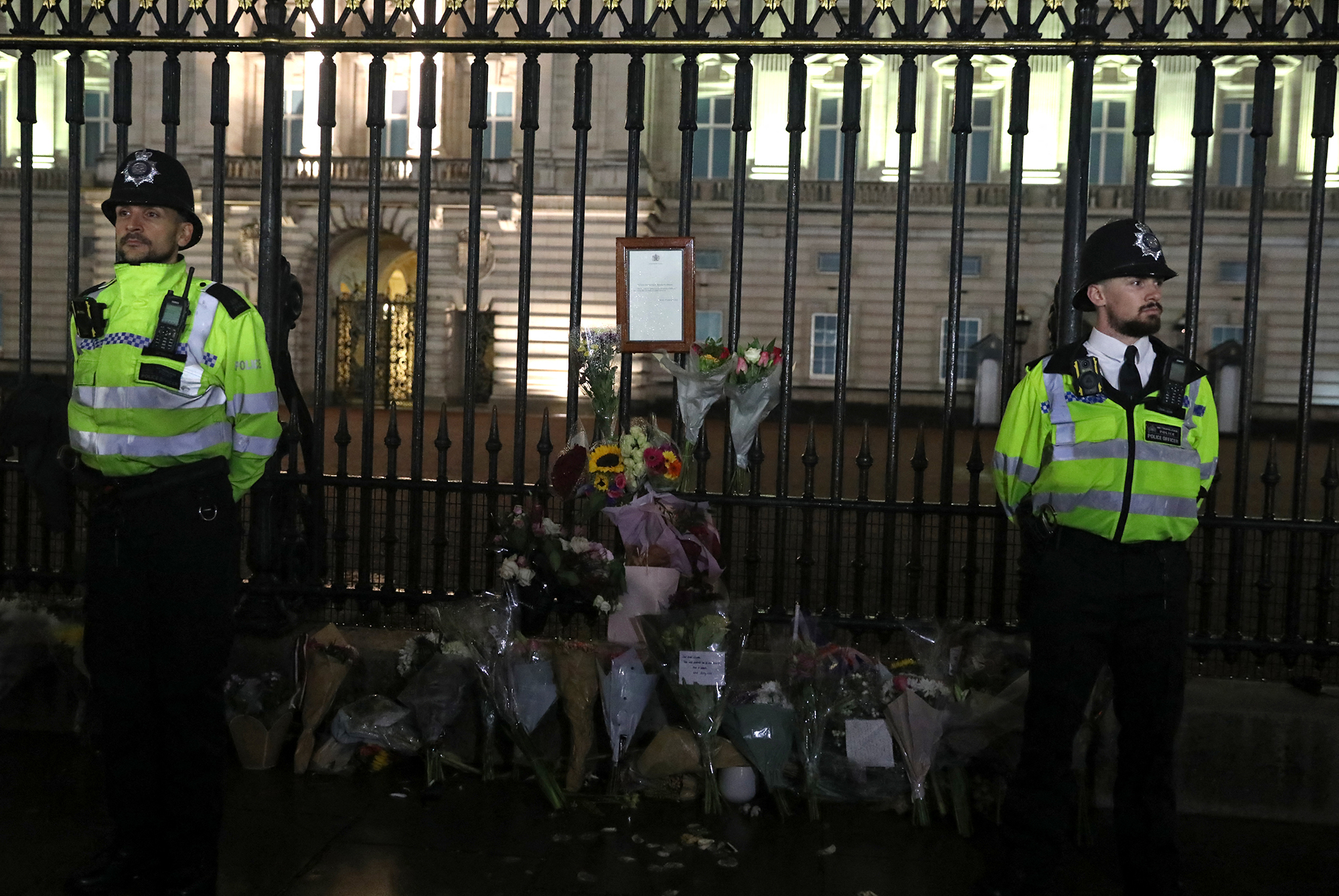 Polizeibeamte stehen vor einer Mitteilung über den Tod von Königin Elisabeth II. am Geländer vor dem Buckingham Palast (Bild: Isabel Infantes/AFP)