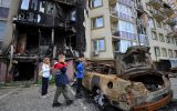 Kinder vor zerstörtem Haus und Auto
