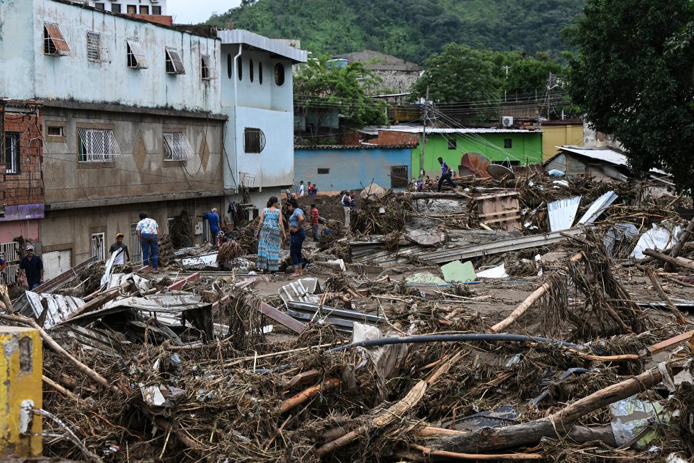 Anwohner stehen inmitten der Trümmer zerstörter Häuser, die von einem Erdrutsch während starker Regenfälle in Las Tejerias im venezolanischen Bundesstaat Aragua weggespült wurden (Bild: Yuri Cortez/AFP)