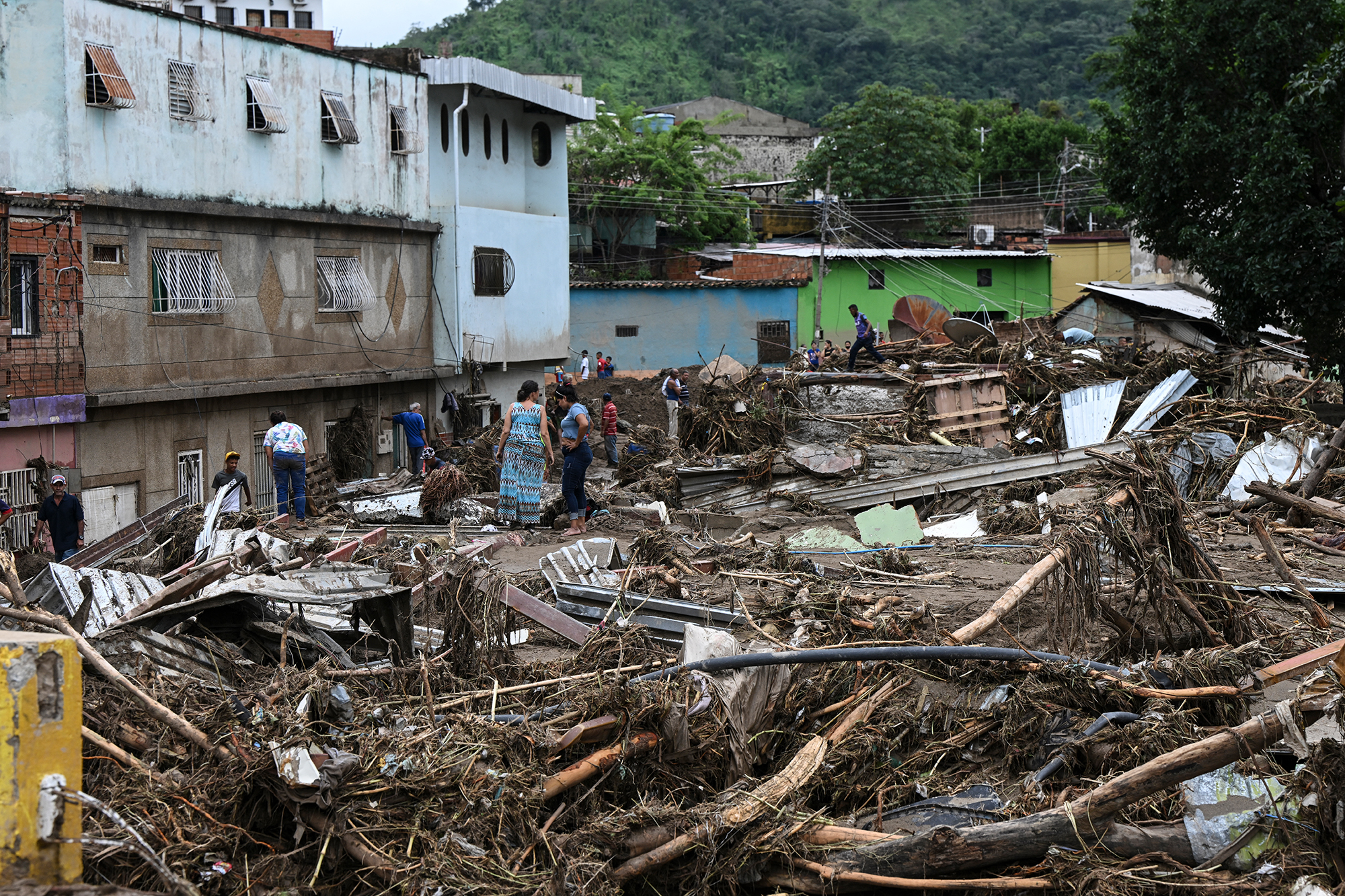 Anwohner stehen inmitten der Trümmer zerstörter Häuser, die von einem Erdrutsch während starker Regenfälle in Las Tejerias im venezolanischen Bundesstaat Aragua weggespült wurden (Bild: Yuri Cortez/AFP)