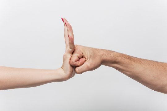 Männerfaust wird von ausgestreckter Frauenhand gestoppt