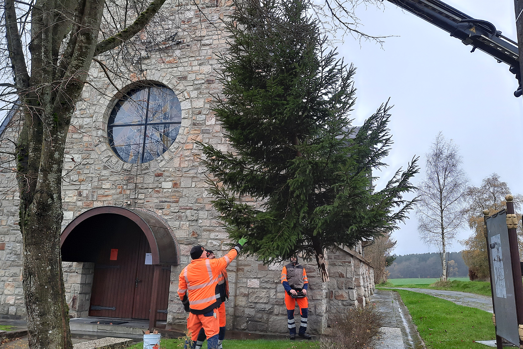 Der Bauhof St. Vith installiert die Weihnachtsdekoration an der Kirche in Hinderhausen (Bild: Chantal Delhez/BRF)