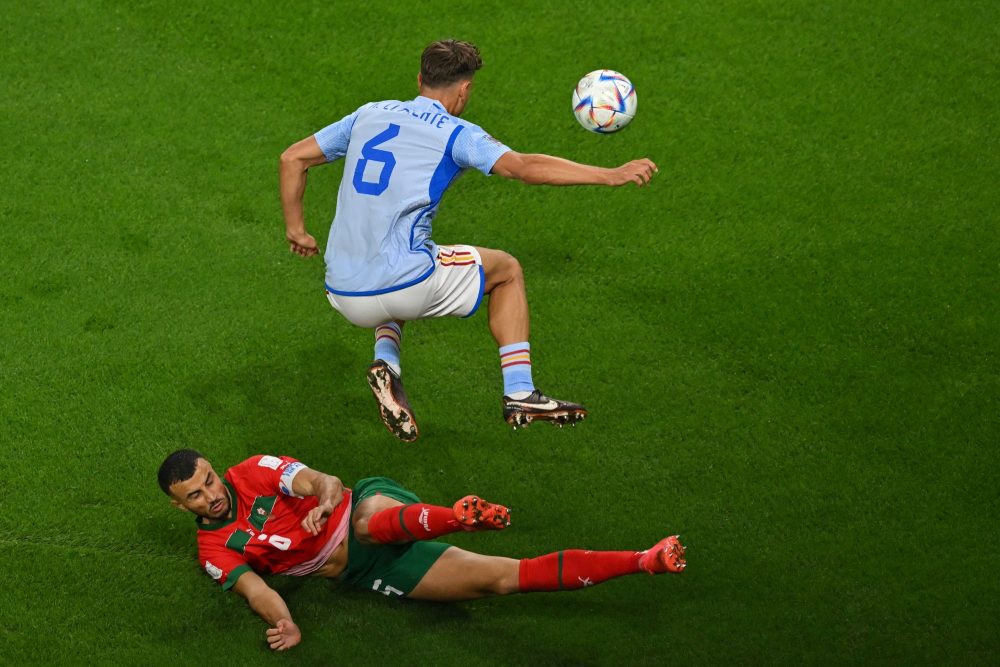 Spain's midfielder #06 Marcos Llorente jumps over Morocco's defender #06 Romain Ghanem Saiss during the Qatar 2022 World Cup round of 16 football match between Morocco and Spain at the Education City Stadium in Al-Rayyan, west of Doha on December 6, 2022. (Photo by Glyn KIRK / AFP)