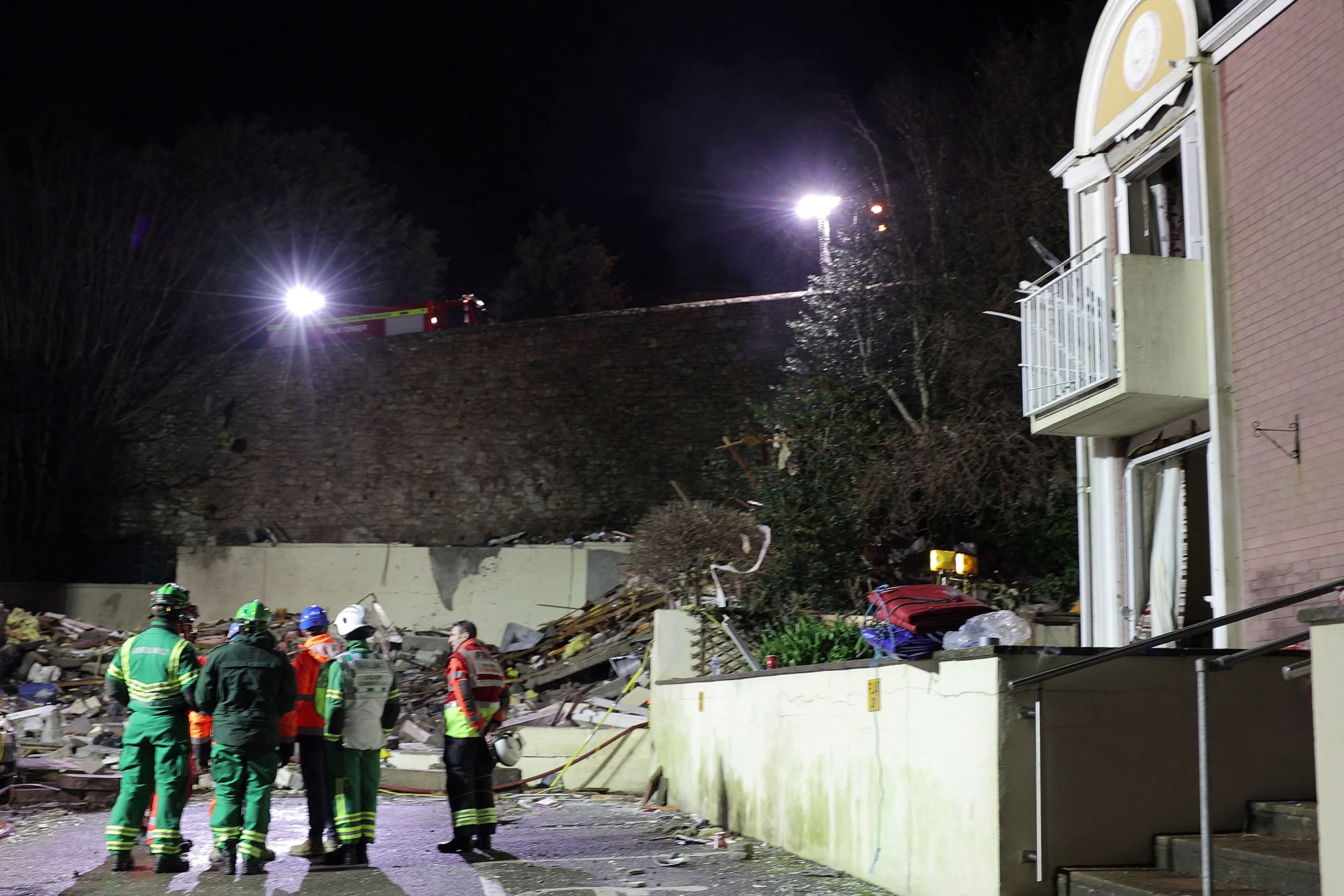 Feuerwehrleute stehen nach der Explosion in der Hafenstadt Saint Helier auf der Kanalinsel vor den Trümmern eines Wohnblocks (Bild: Government of Jersey/AFP)