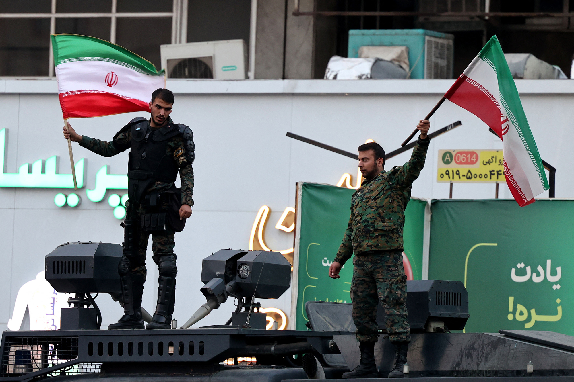 Mitglieder der iranischen Bereitschaftspolizei schwenken in Teheran Flaggen während eines Spiels der iranischen Nationalmannschaft bei der WM in Katar (Bild: Atta Kenare/AFP)