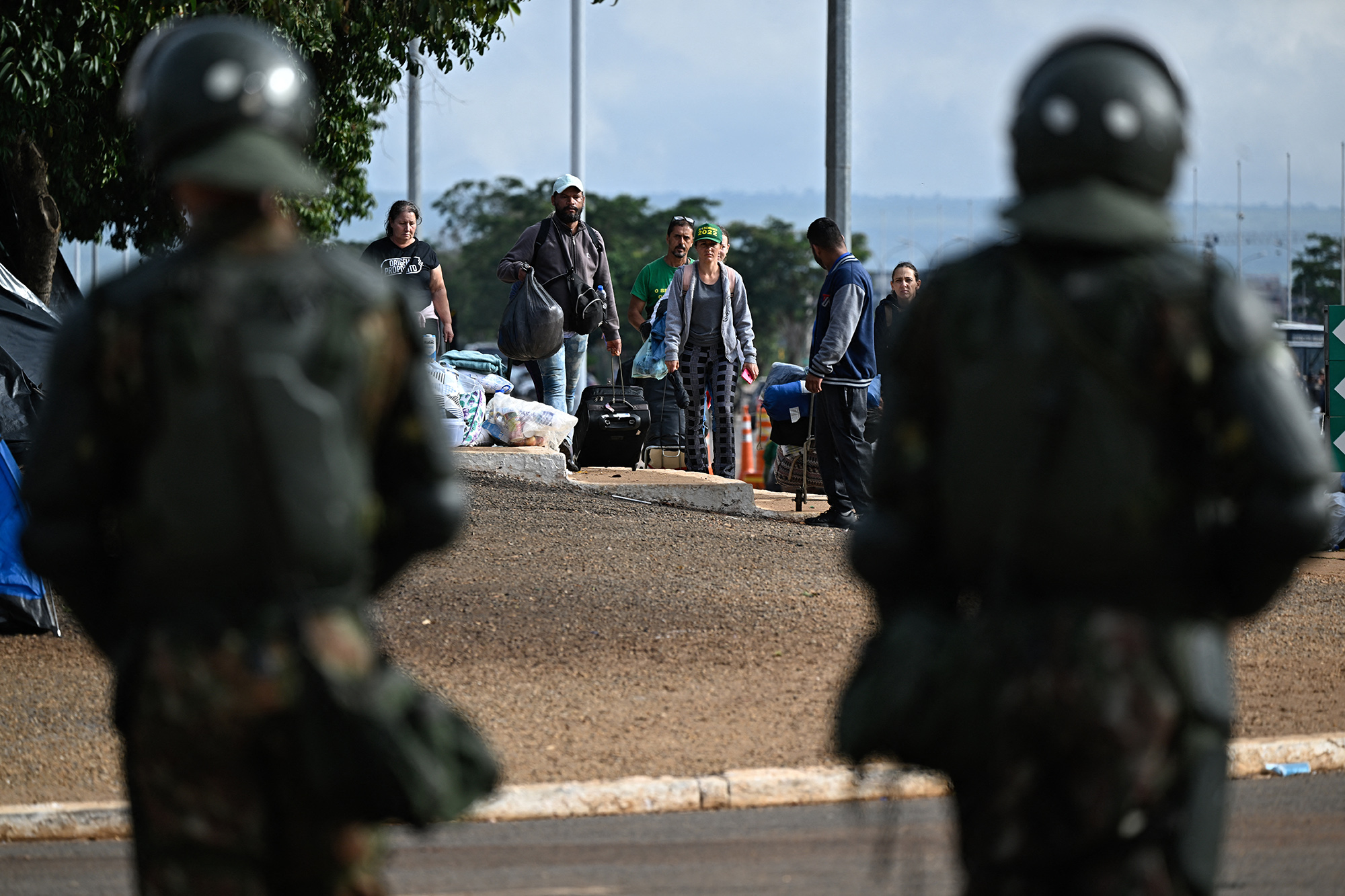 Anhänger von Ex-Präsident Jair Bolsonaro verlassen das Camp unter Aufsicht von Soldaten (Bild: Mauro Pimentel/AFP)
