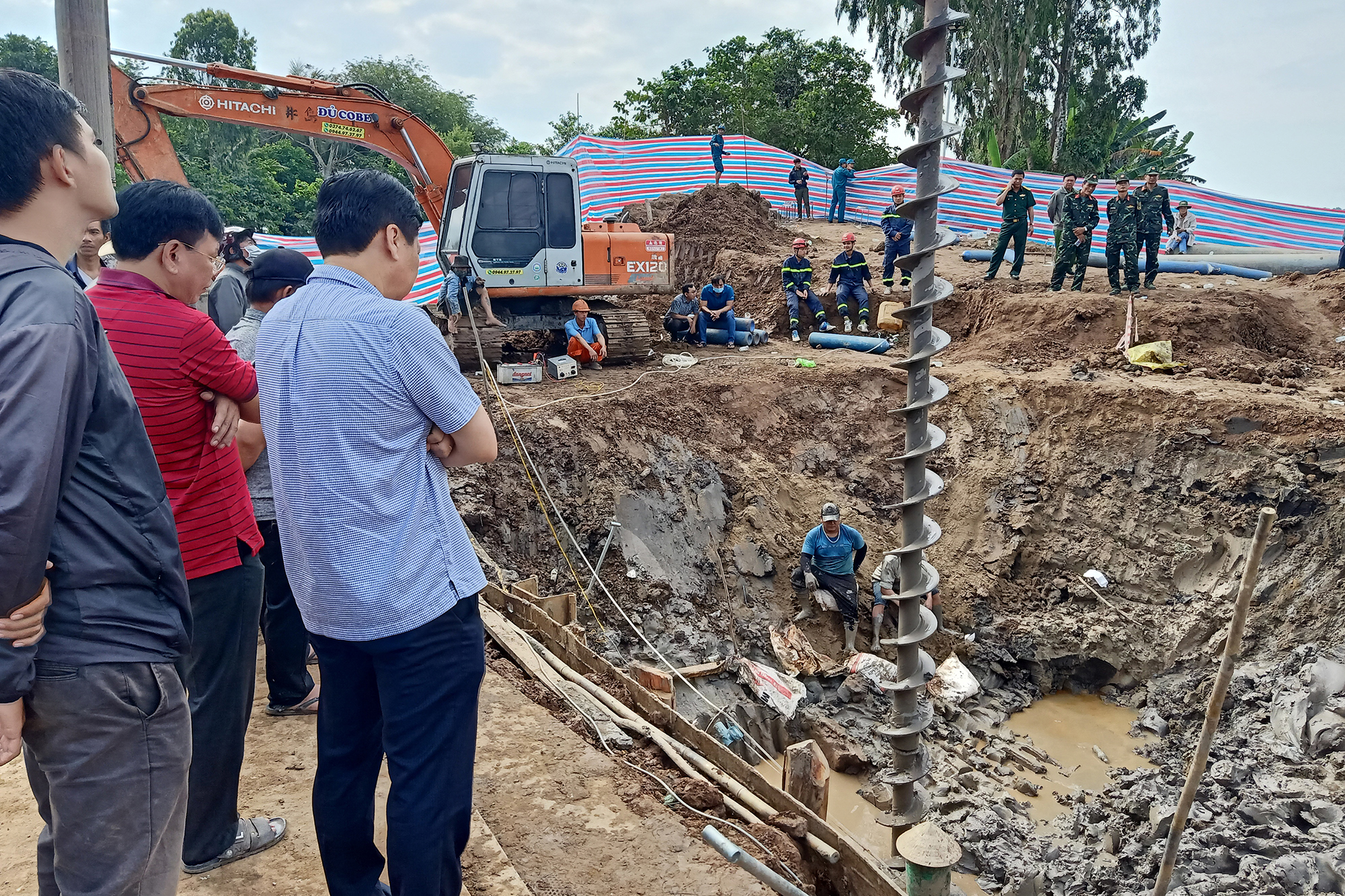 Retter an der Stelle, an der der Junge auf einer Baustelle in der vietnamesischen Provinz Dong Thap vermutlich in einen 35 Meter tiefen Schacht gefallen ist (Bild: STR/AFP)
