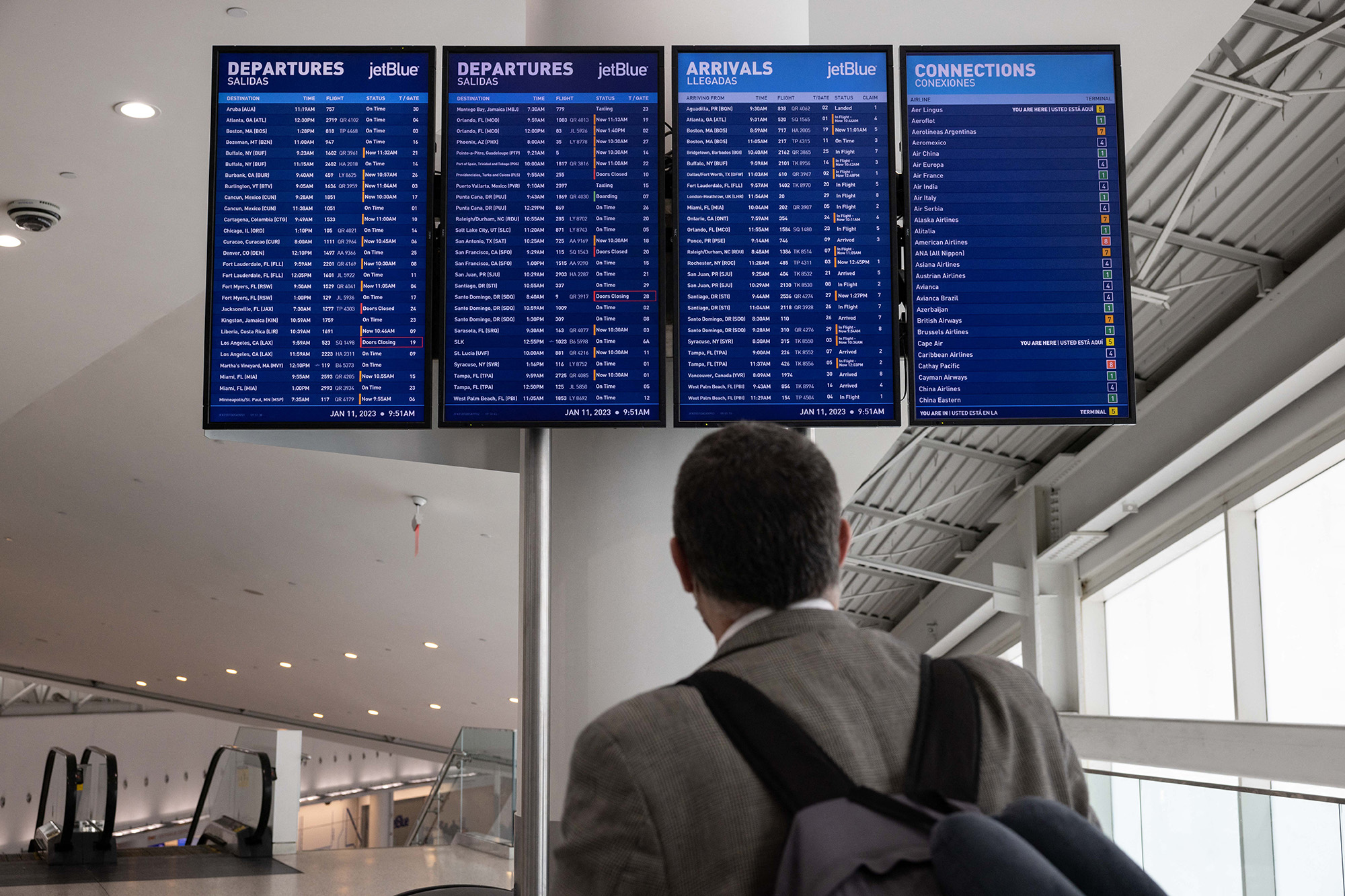 People look at the flight schedules at the JFK International Airport on January 11, 2023 in New York. - The US Federal Aviation Authority said Wednesday that normal flight operations "are resuming gradually" across the country following an overnight systems outage that grounded departures. (Photo by Yuki IWAMURA / AFP)