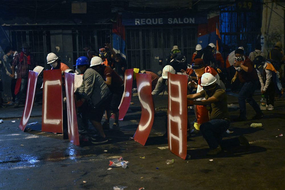 Peru: Demonstranten in Lima beschützen sich vor Tränengaseinsatz der Polizei (Bild: Ernesto Benavides/AFP)