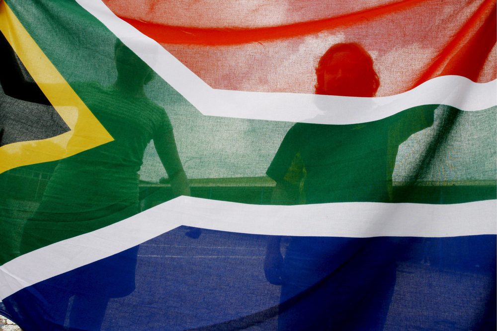 Kinder halten die Flagge Südafrikas hoch (Illustrationsbild: Kim Ludbrook/EPA)