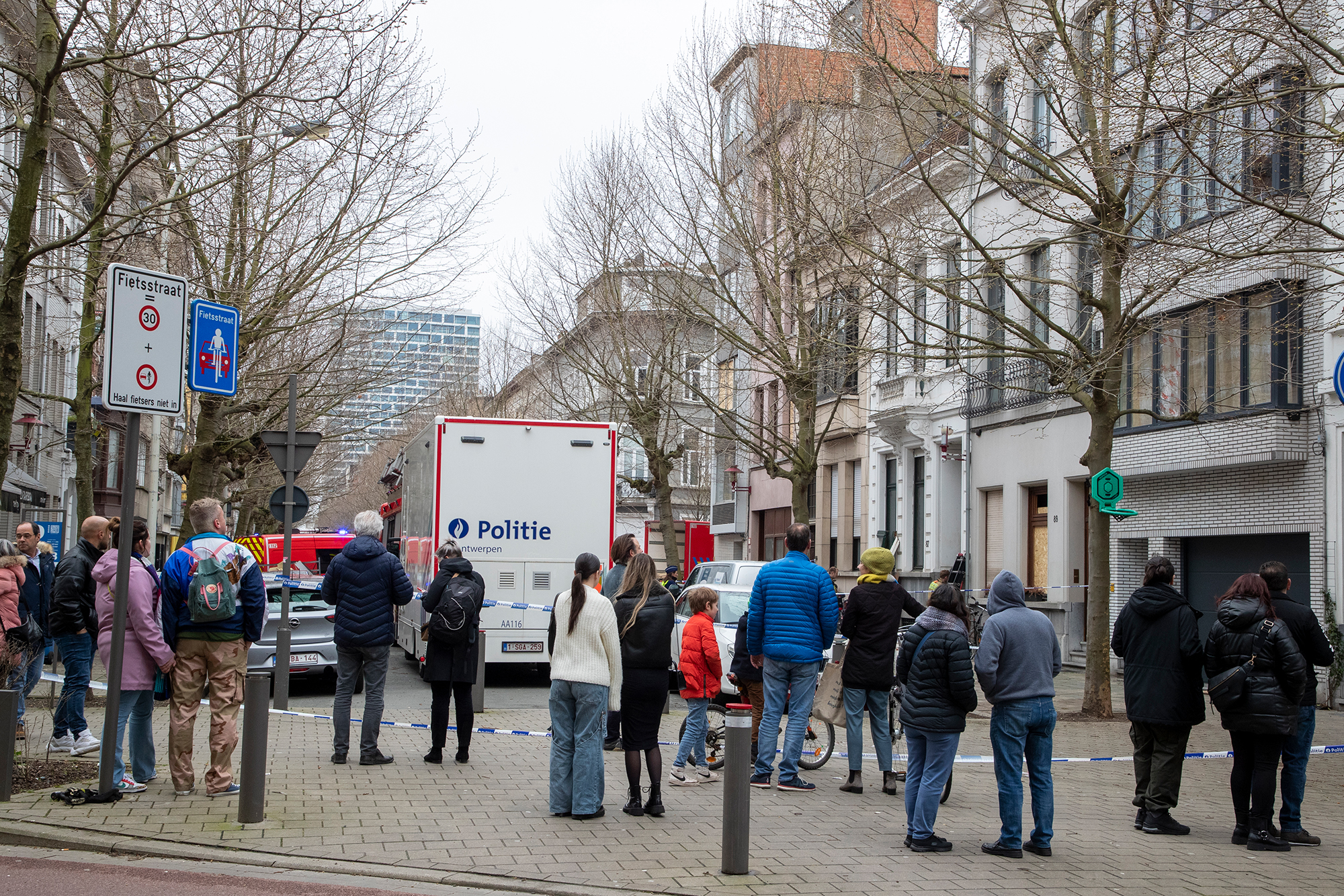 Passanten beobachten die Arbeit von Polizei und Feuerwehr am Explosionsort in der Osystraat in Antwerpen (Bild: Nicolas Maeterlinck/Belga)