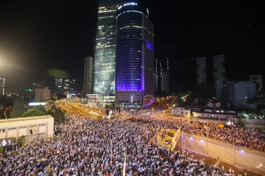 Demonstrators lift flags and placards during a rally to protest the Israeli government's judicial overhaul bill in Tel Aviv, on April 22, 2023. (Photo by JACK GUEZ / AFP)