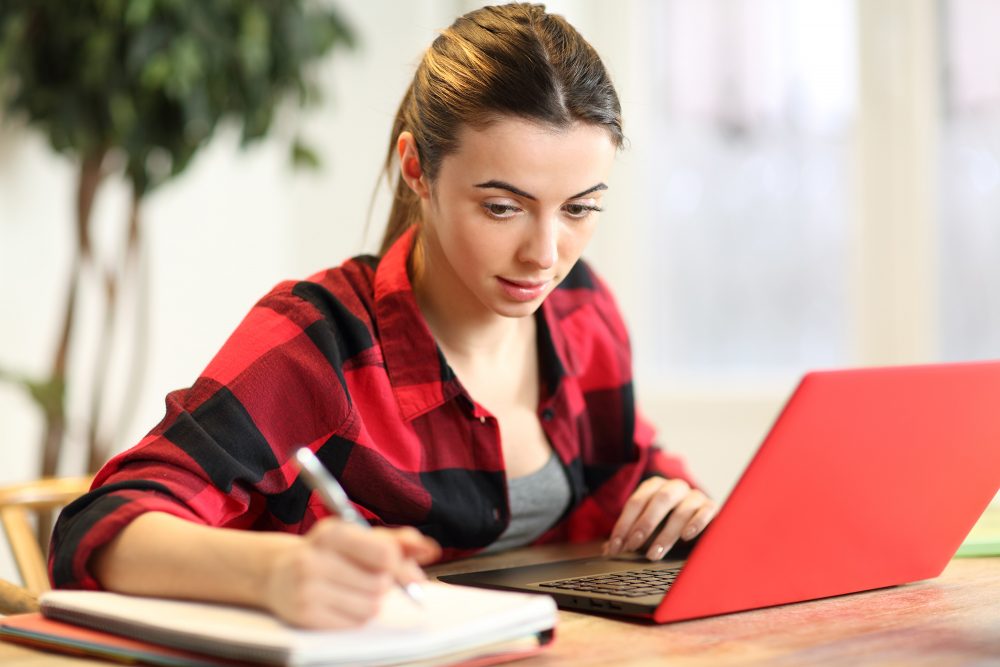 Schülerin lernt am Laptop mit Notizblock