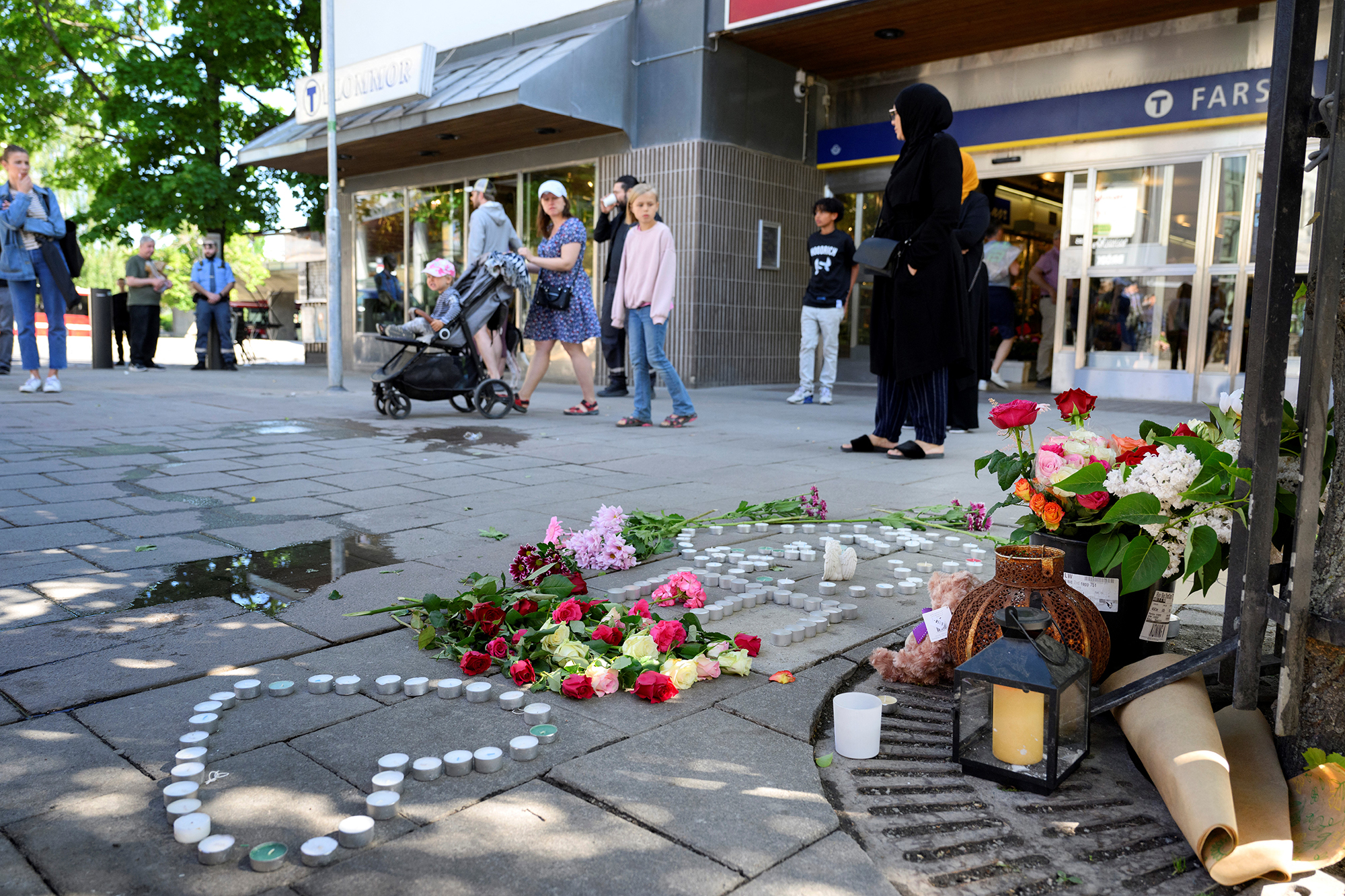 Blumen und Kerzen auf dem Bürgersteig am Tag nach der Schießerei im Einkaufszentrum von Farsta, südlich von Stockholm (Bild: Jessica Gow/TT/TT News Agency/AFP)