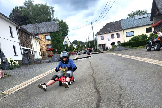 Bobby-Car-Rennen durch Crombach (Bild: Christophe Ramjoie/BRF)