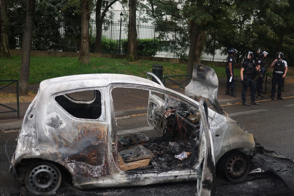 Polizisten neben einem ausgebrannten Auto in Nanterre (Bild: Charly Triballeau/AFP)