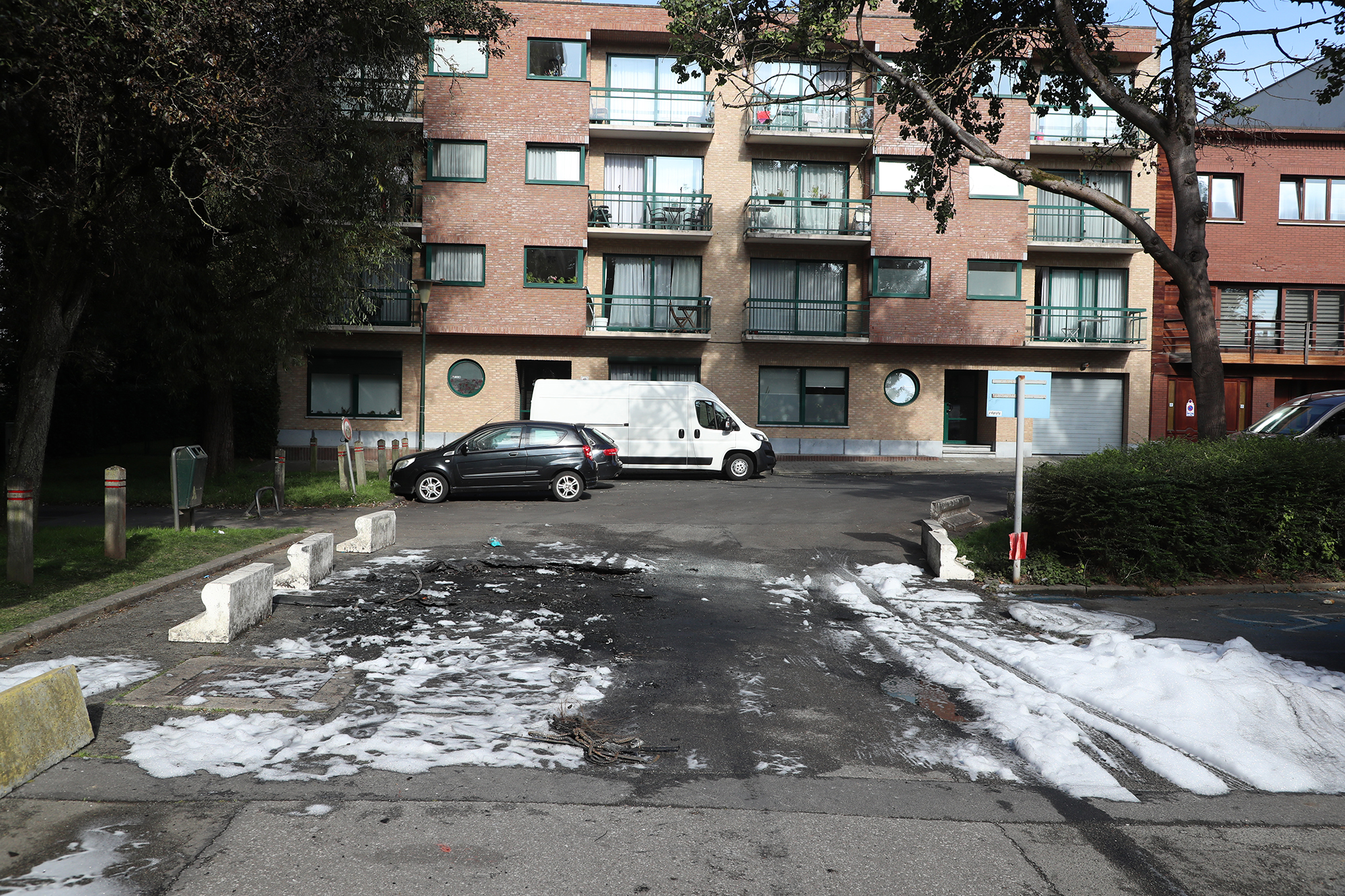 Löschschaum auf dem Parkplatz, auf dem das ausgebrannte Auto der Verdächtigen gefunden wurde (Bild: Nicolas Maeterlinck/Belga)