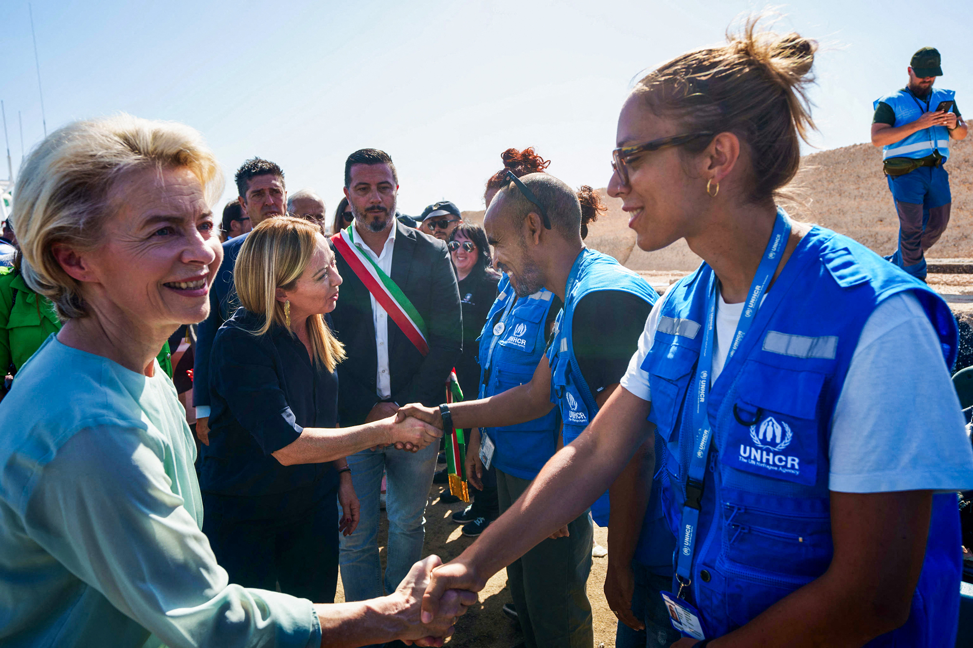 EU-Kommissionspräsidentin Ursula von der Leyen (l.), und Italiens Ministerpräsidentin Giorgia Meloni (2.v.l.) bei der Begrüßung von Mitgliedern des Hohen Flüchtlingskommissars der Vereinten Nationen (UNHCR) während ihres Besuchs auf der italienischen Insel Lampedusa (Bild: Handout/ANSA/AFP)