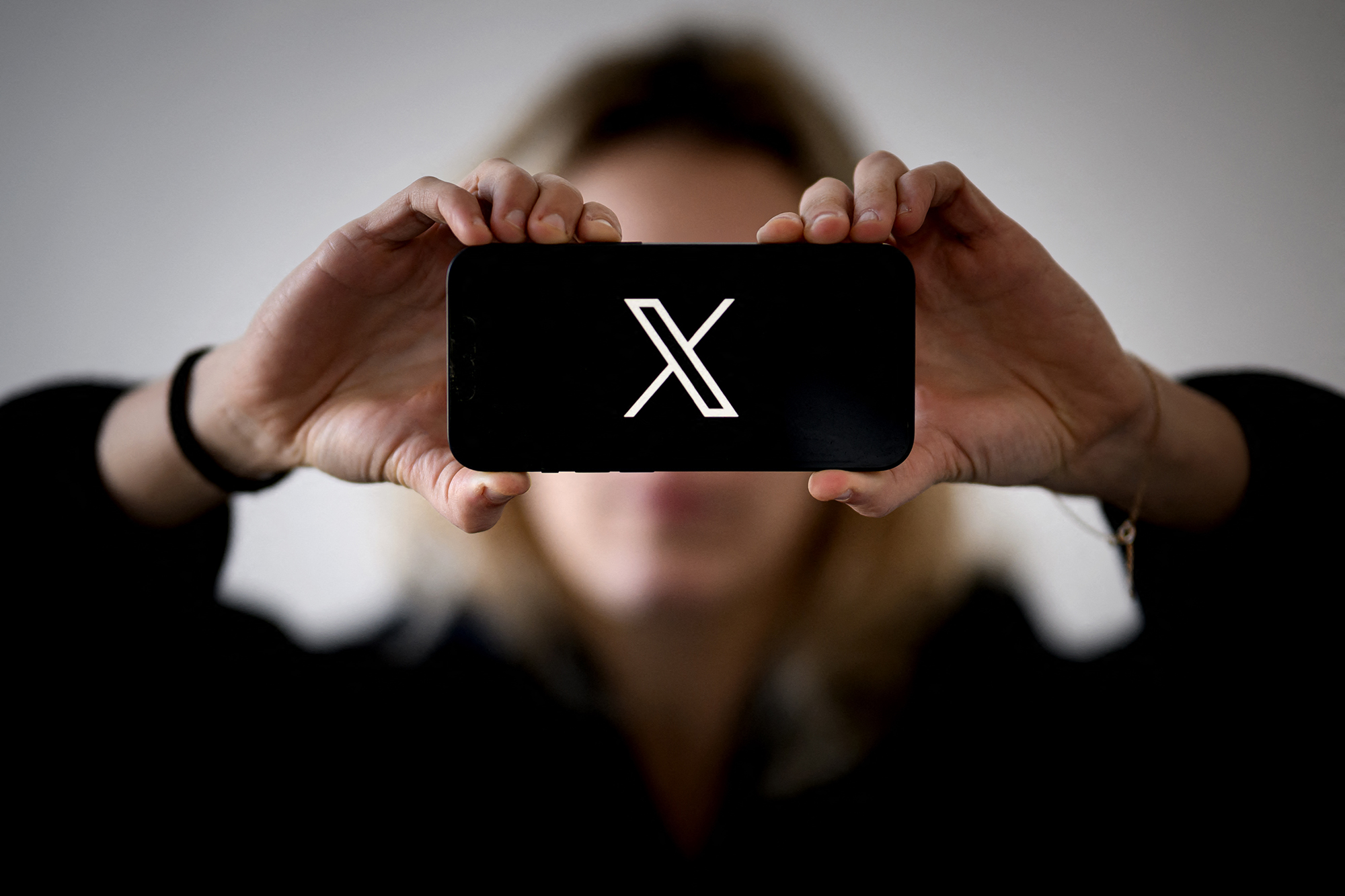 Frau mit Smartphone und X-Logo