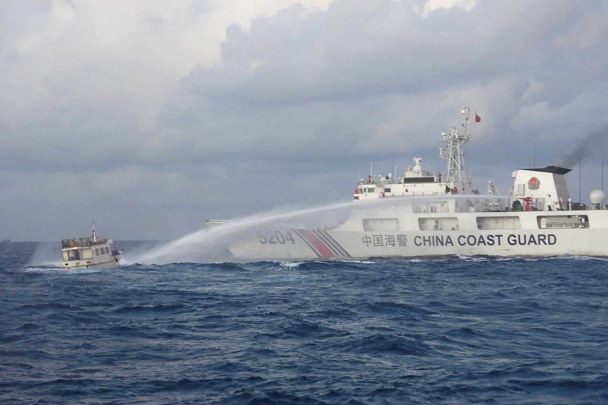 Der Videoausschnitt zeigt ein Schiff der chinesischen Küstenwache, das Wasserwerfer gegen ein philippinisches Versorgungsboot einsetzt (Bild: Handout/Philippine Coast Guard (PCG)/AFP)